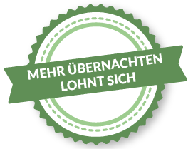 Plakette mit der Aufschrift "Mehr übernachten lohnt sich". Dargestellt ist ein runder Kreis mit Wellen an der Außenseite, über dem ein grünes Banner angebracht ist. Auf diesem Banner ist der Schriftzug "Mehr Übernachten Lohnt sich" zu lesen.